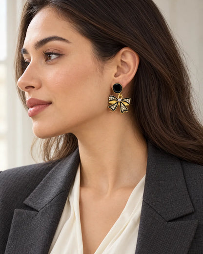 Side view of a model in a dark blazer wearing the black bow dangle earrings