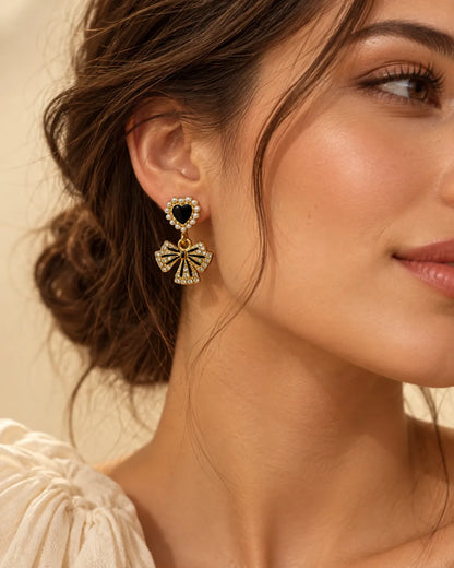 Close-up profile of a model wearing the black heart and bow dangle earring