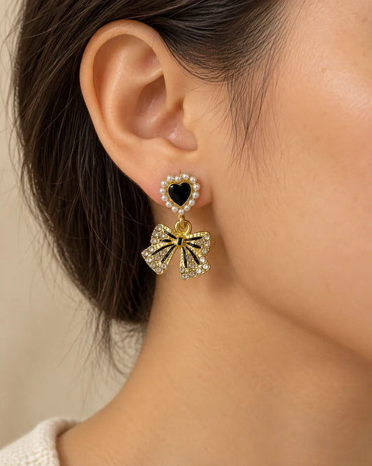 Close-up of a model's ear wearing the black heart and bow dangle earring