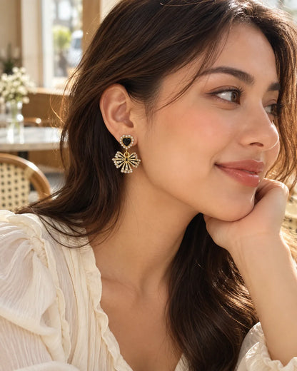Model in a cream blouse wearing the black heart and bow earrings