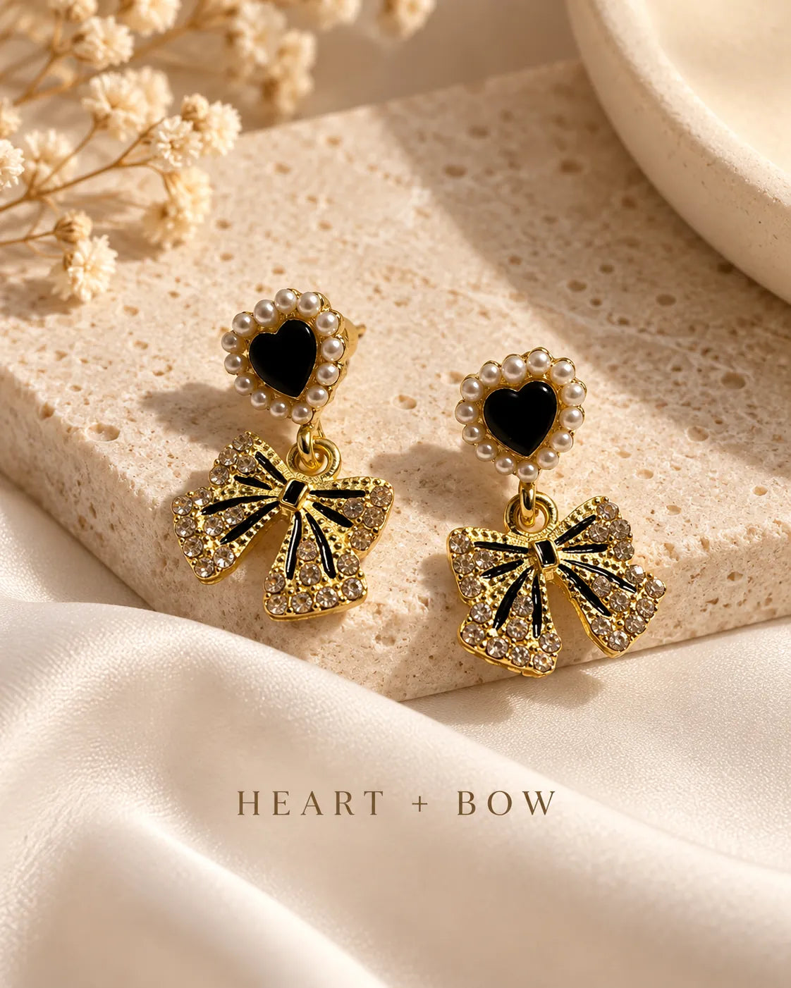 Black heart and bow earrings on a stone surface with heart and bow caption