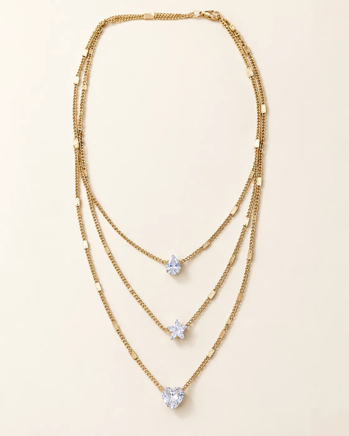 Gold-tone Celestial Sparkle three-layer crystal necklace on cream