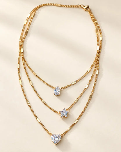 Gold three-strand crystal necklace laid flat on a cream background