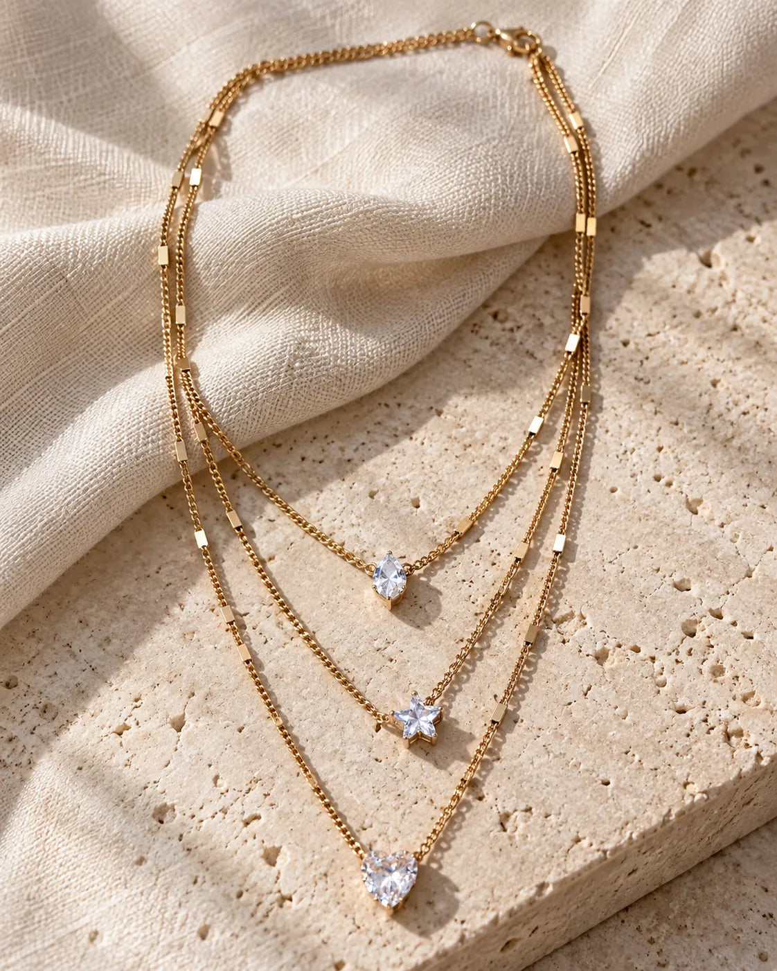 Gold Celestial Sparkle necklace draped over stone and linen