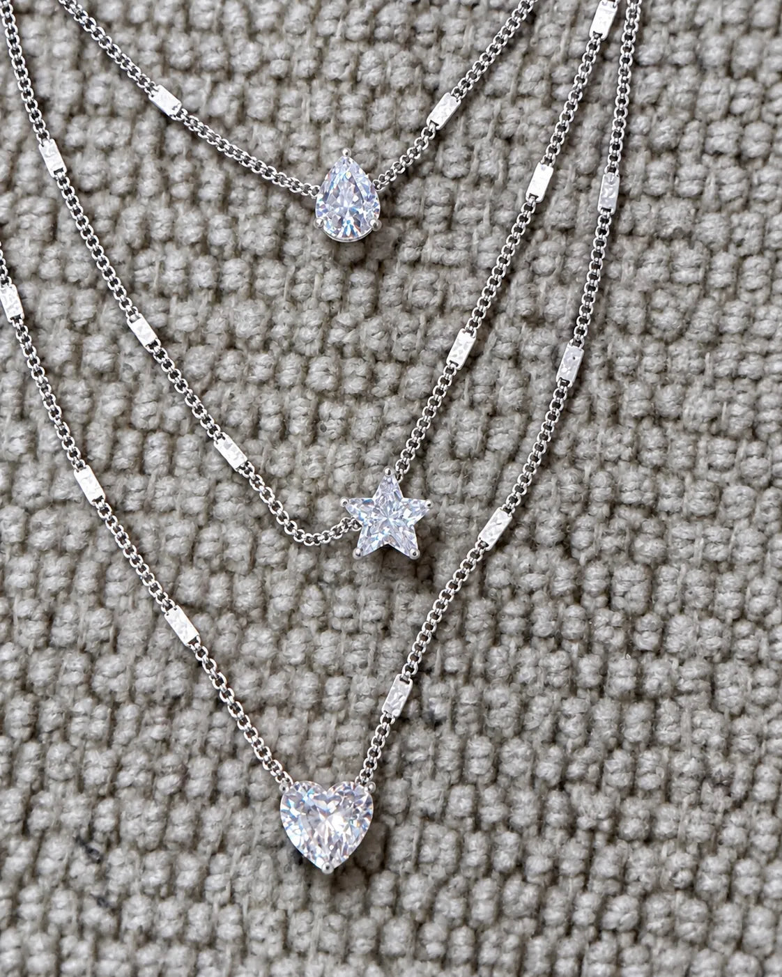 Close-up of the silver pear, star and heart crystals on grey knit fabric