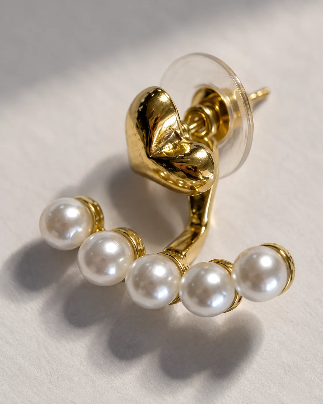 Close-up of the gold heart knot and curved row of pearl-look beads
