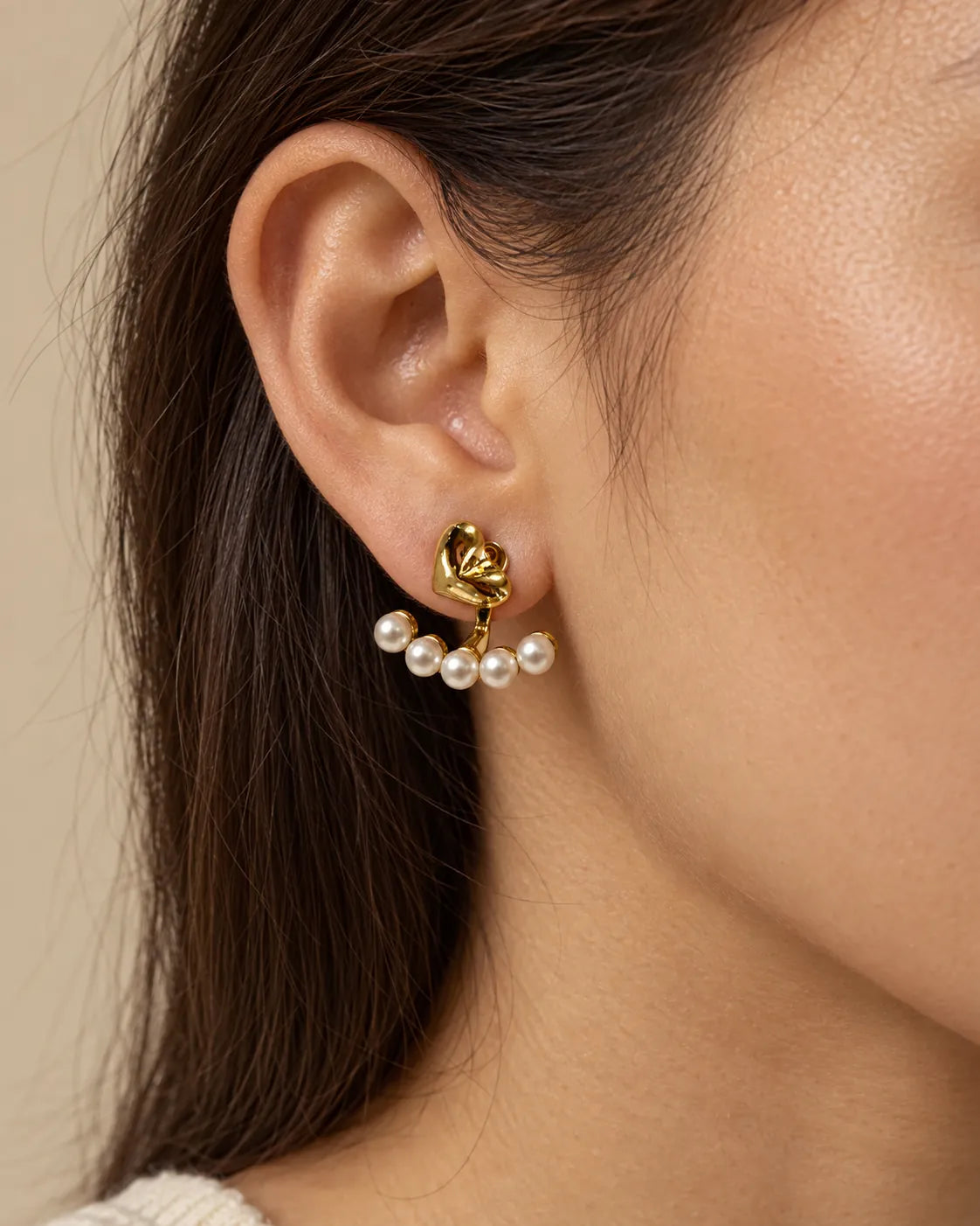 Close-up of a model's ear wearing the gold heart and pearl-look stud