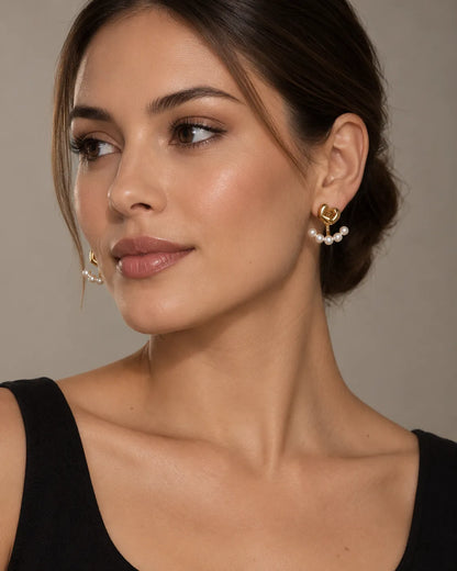 Model in a black top wearing the gold heart and pearl-look studs