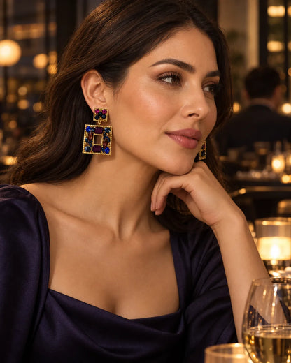 Model in a navy dress at an evening venue wearing the plum statement earrings