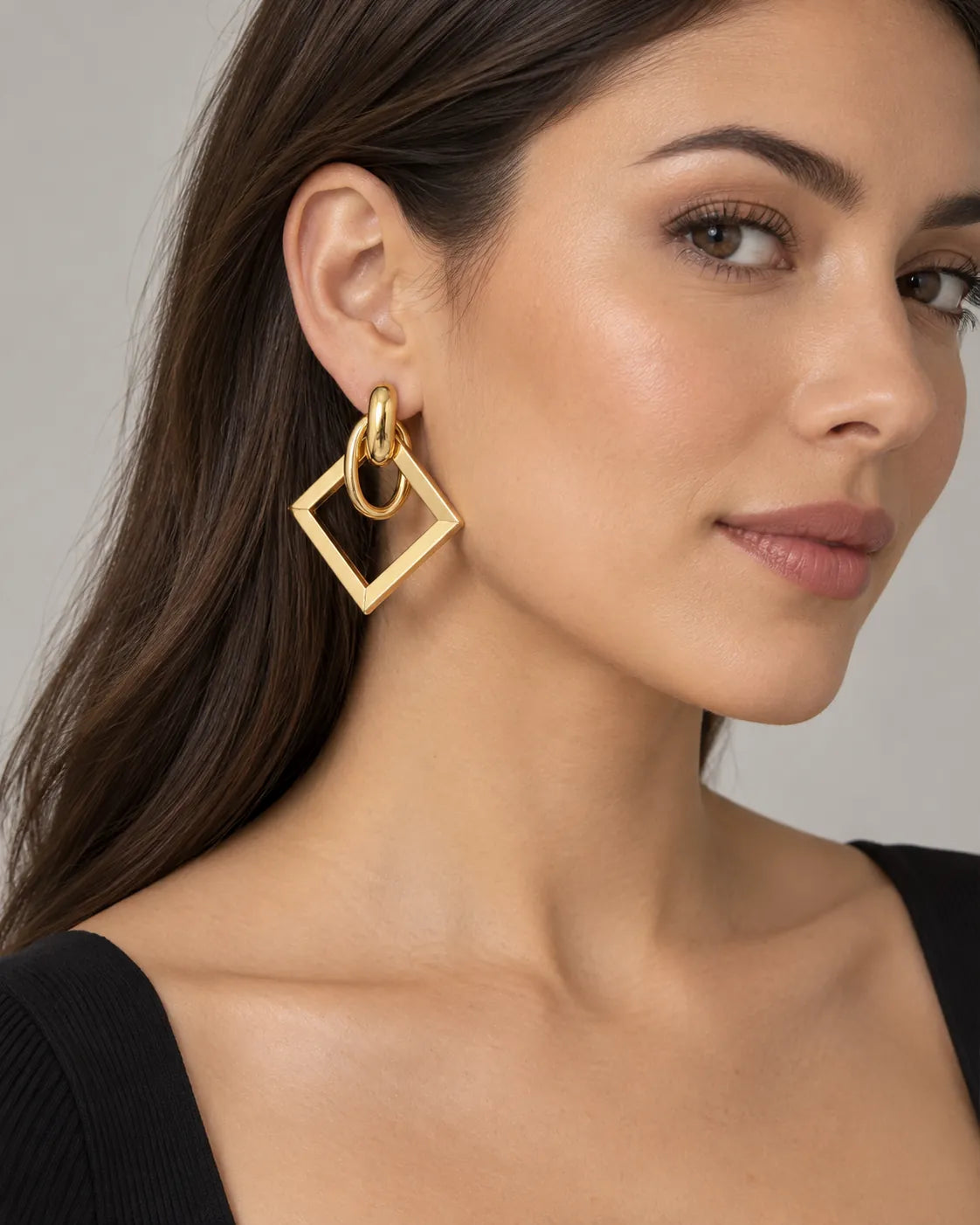 Model in a black top wearing the gold geometric square drop earrings