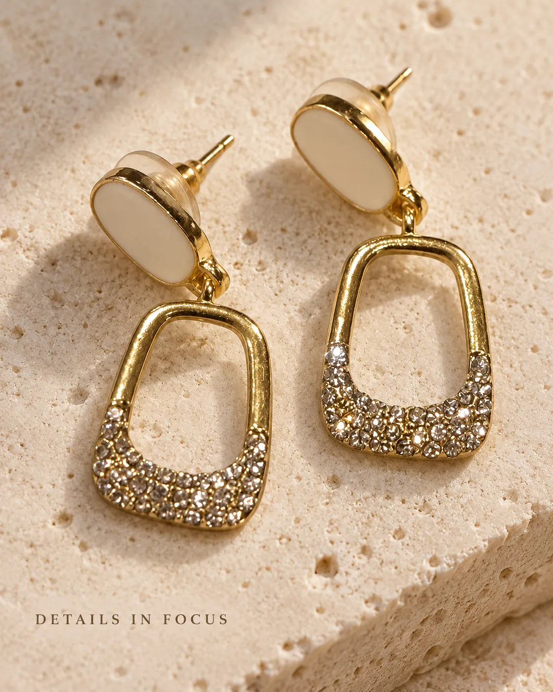 White enamel oval drop earrings on a stone surface with Details In Focus text