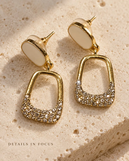 White enamel oval drop earrings on a stone surface with Details In Focus text