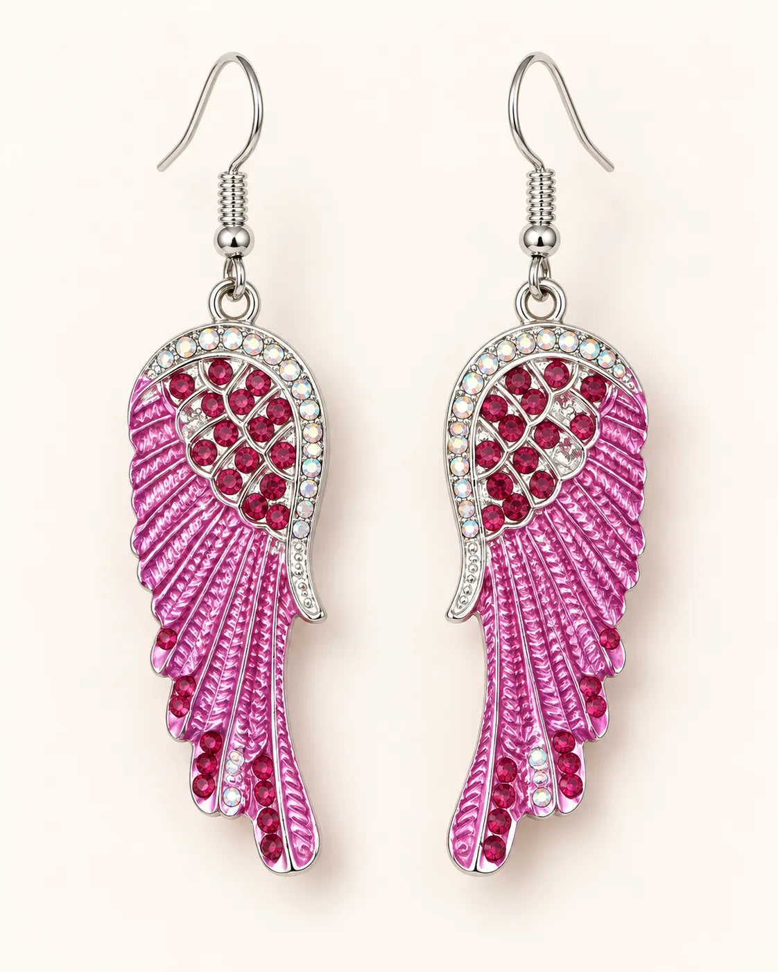 Pink enamel angel wing crystal earrings with fish-hook wires on a cream background