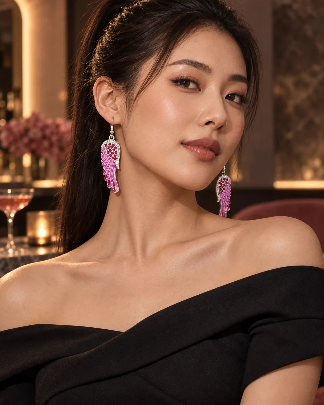 Model in a black off-shoulder top wearing the pink angel wing earrings