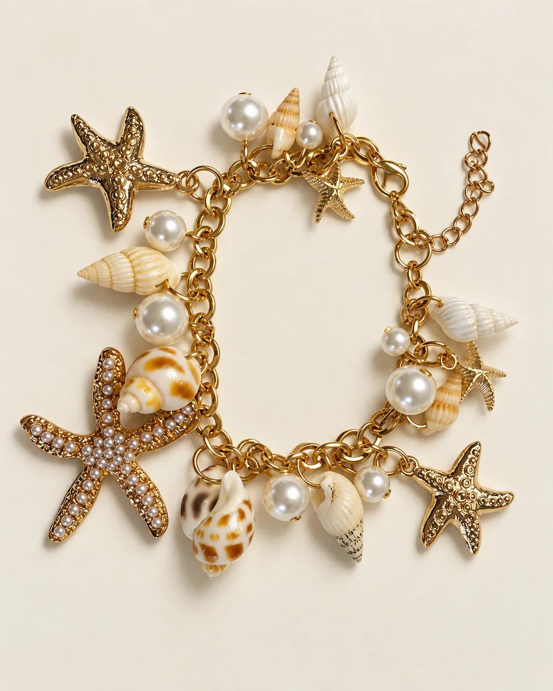 Gold starfish and shell charm bracelet laid out on a cream background