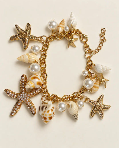 Gold starfish and shell charm bracelet laid out on a cream background