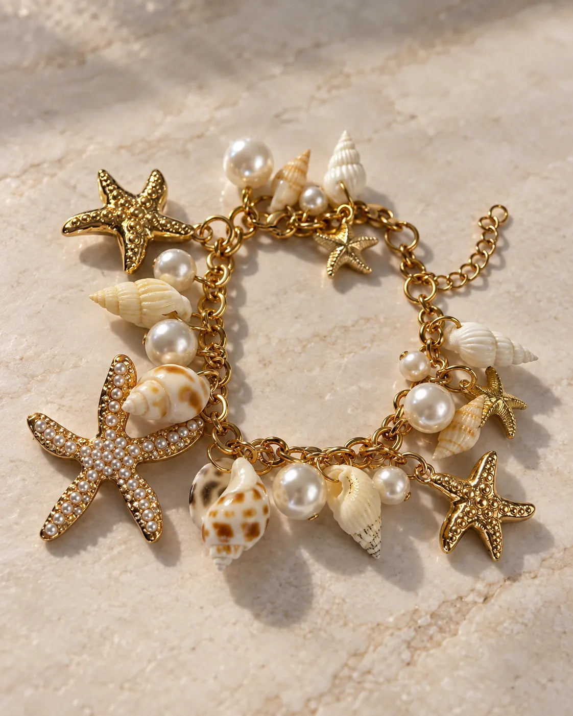 Gold charm bracelet with starfish, shells and pearl-look beads on sand-toned fabric