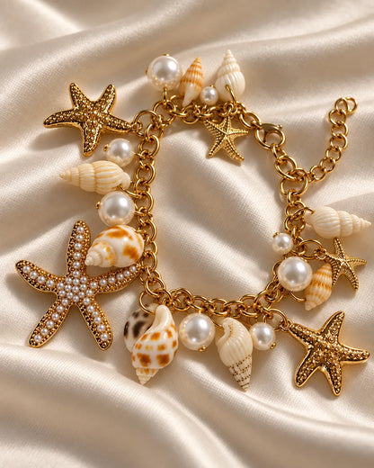 Gold starfish charm bracelet on a sandy textured surface