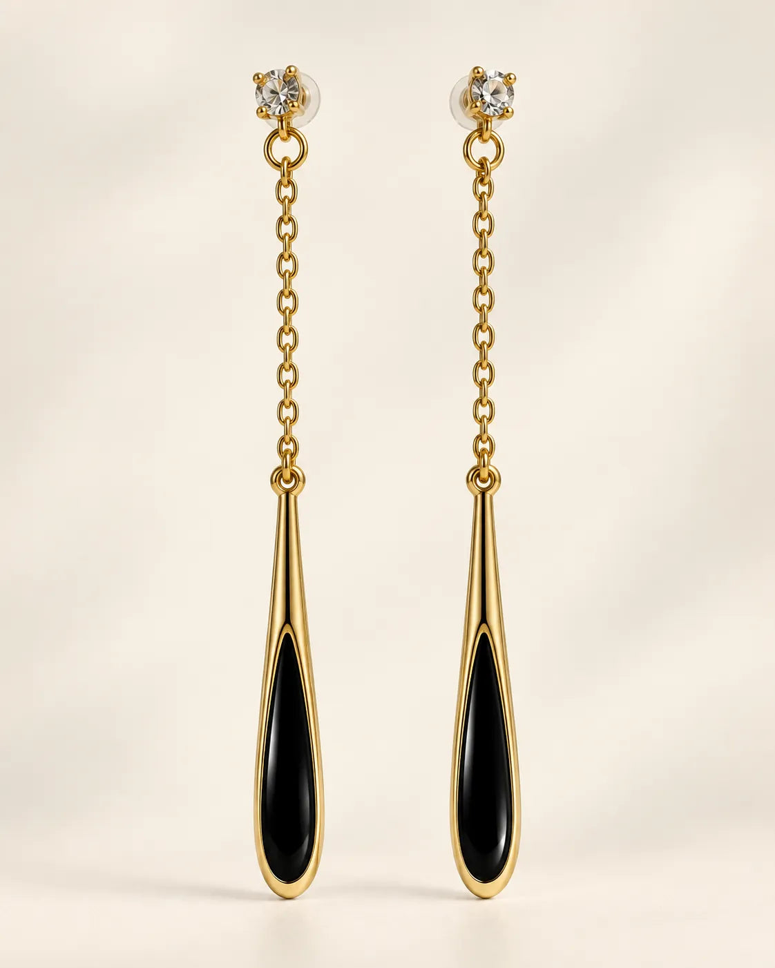 Black teardrop long chain drop earrings with clear crystal studs on a cream background