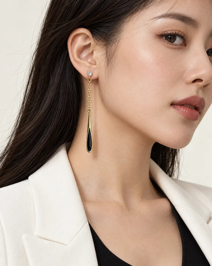 Model in a white blazer with hair tucked back wearing the black chain drop earrings