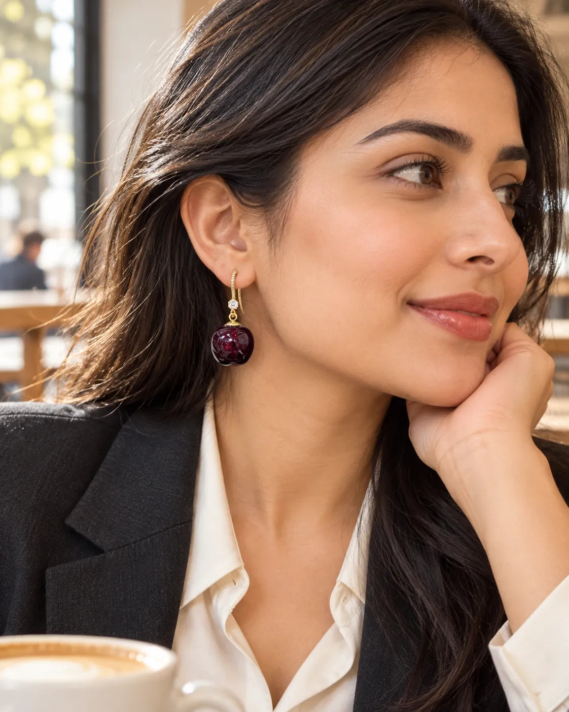 Model in a black blazer at a cafe wearing the red cherry drop earrings