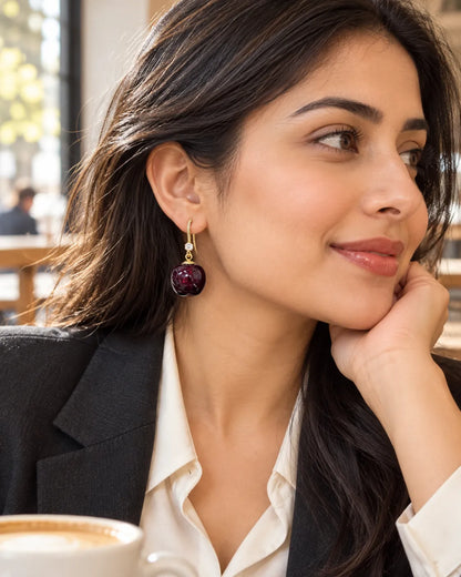 Model in a black blazer at a cafe wearing the red cherry drop earrings