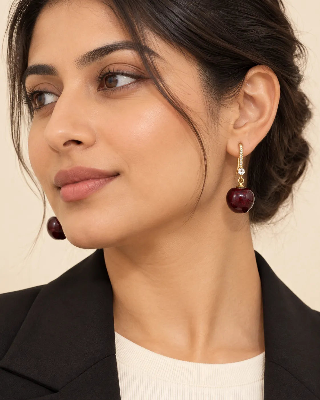 Model in a black blazer wearing the gold-tone cherry drop earrings