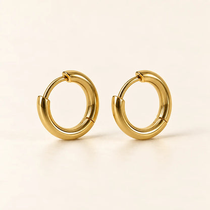 Pair of 18k gold-plated sterling silver huggie hoop earrings on cream
