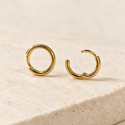 Gold huggie hoops on a stone edge, one closed and one open
