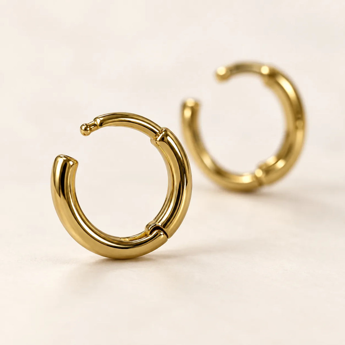 Close-up of gold huggie hoops with one hinge open