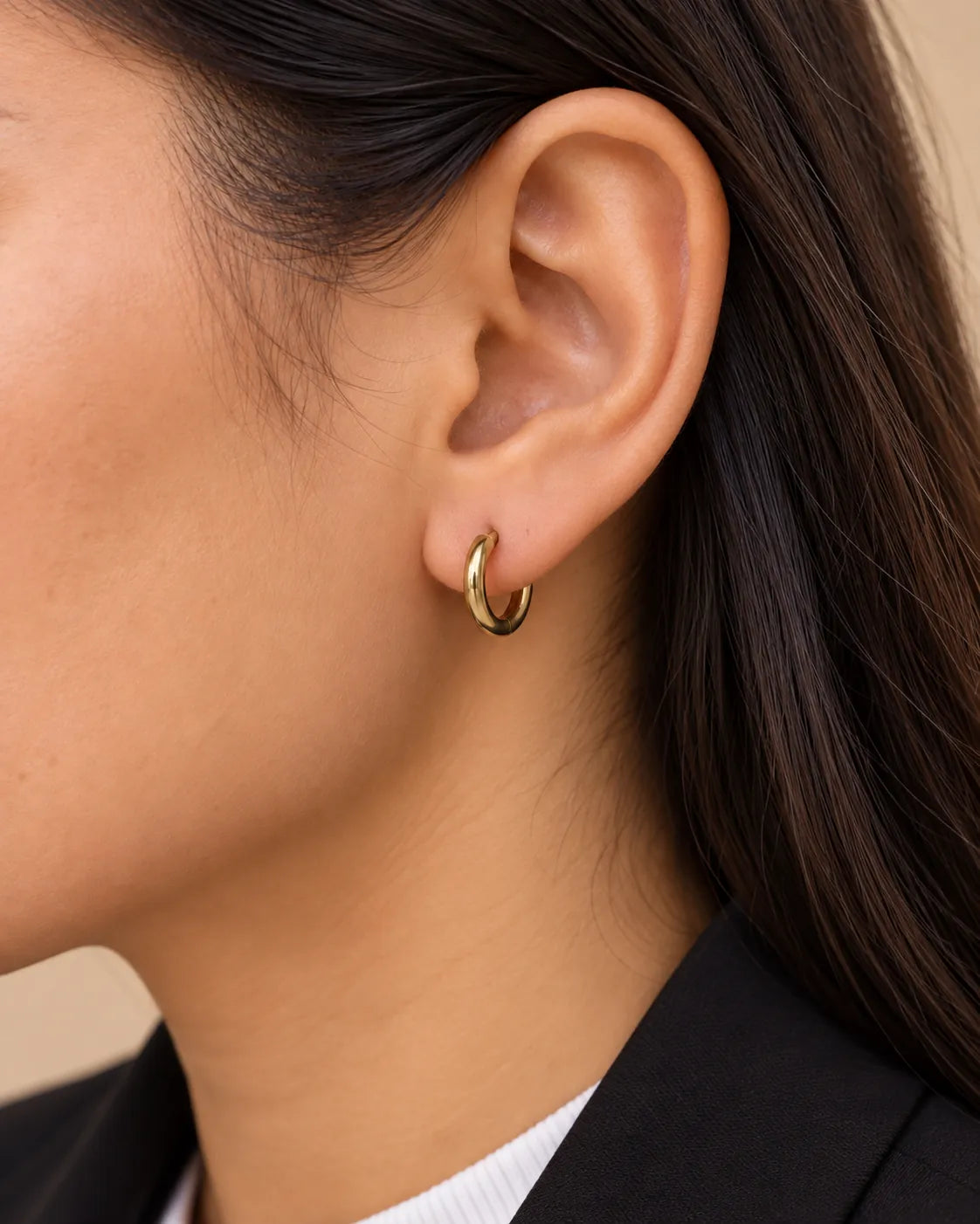 Close-up of a gold huggie hoop earring hugging the lobe