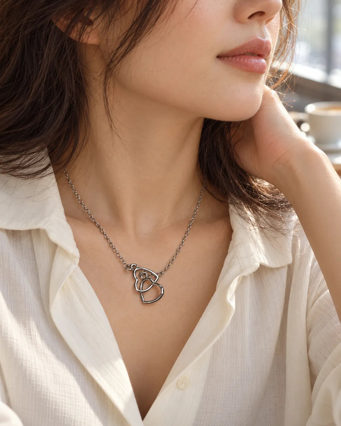 Model in a cream open-collar shirt wearing the interlinked heart pendant