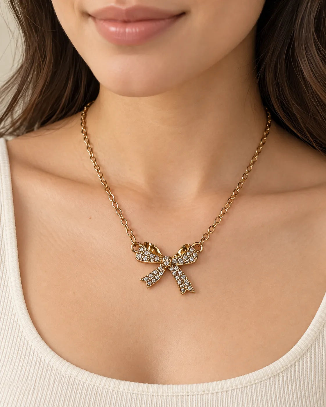 Model in a cream scoop-neck top wearing the gold bow necklace