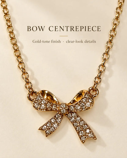 Gold bow necklace with Bow Centrepiece text on a cream background