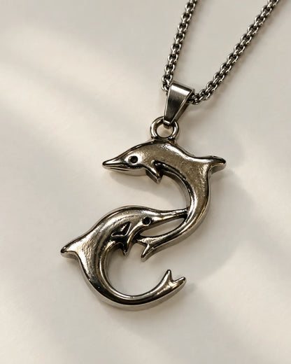 Silver-tone double dolphin pendant necklace on a light grey background