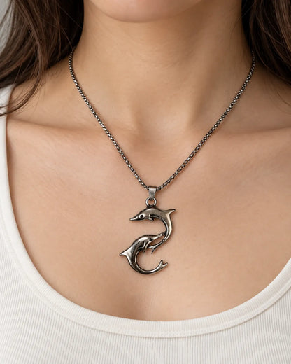 Model in a white scoop-neck top wearing the silver dolphin necklace