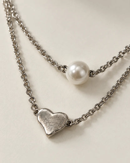 Close-up of the round pearl-look bead and brushed silver-tone heart