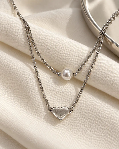 Two-layer silver pearl and heart necklace on cream linen