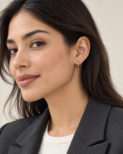 Model in a dark blazer wearing silver huggie hoop earrings
