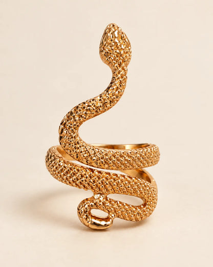 Gold serpent wrap ring with dotted scale texture on a cream background