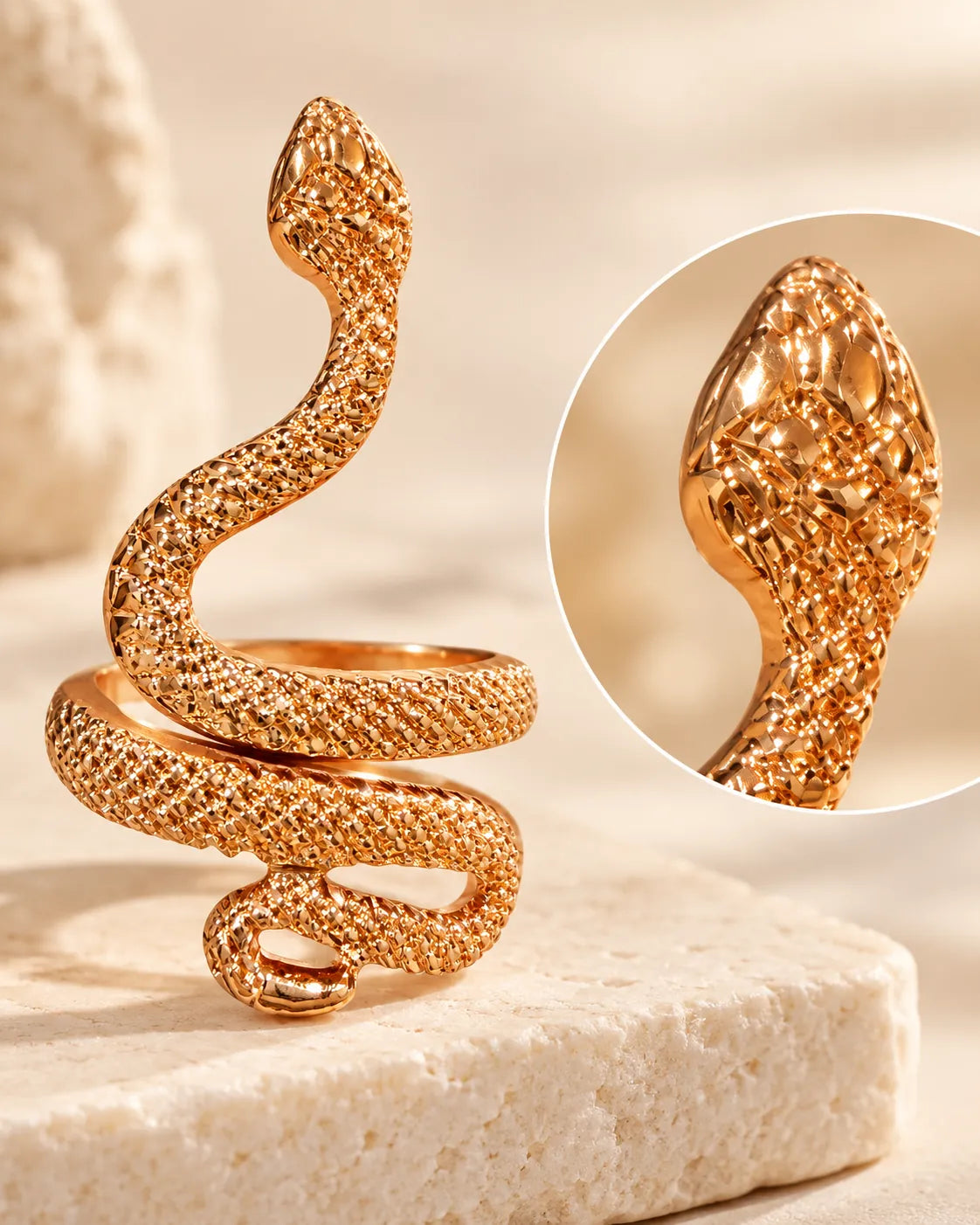 Gold snake ring on a stone block with a close-up inset of the head