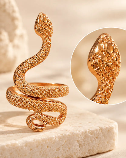Gold snake ring on a stone block with a close-up inset of the head