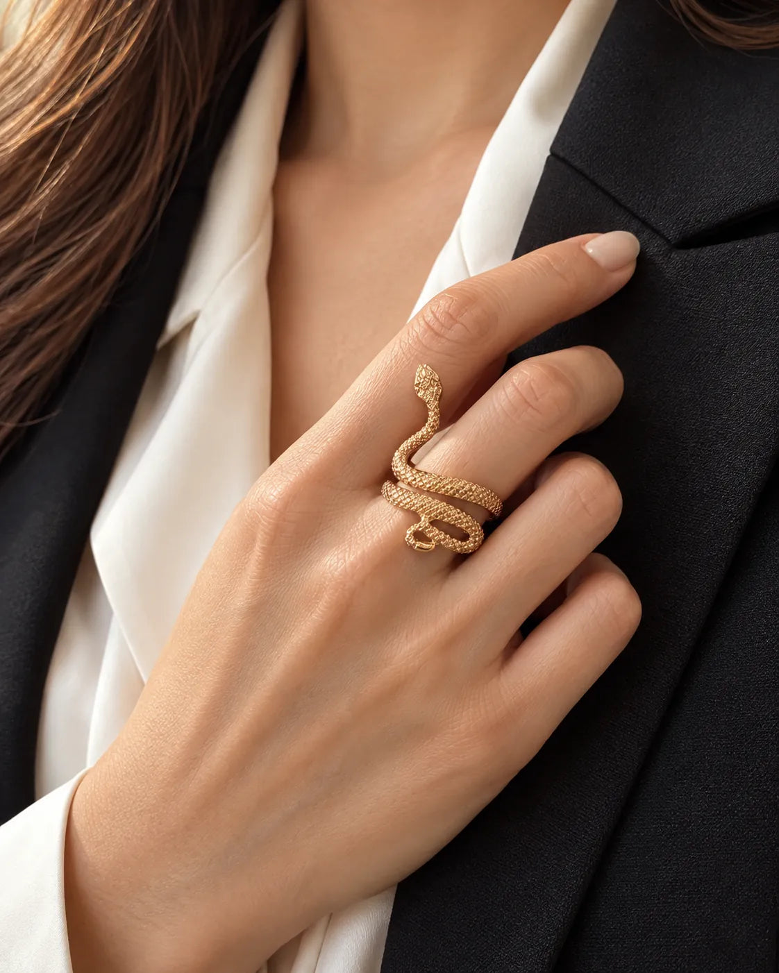Hand against a black blazer wearing the gold serpent wrap ring