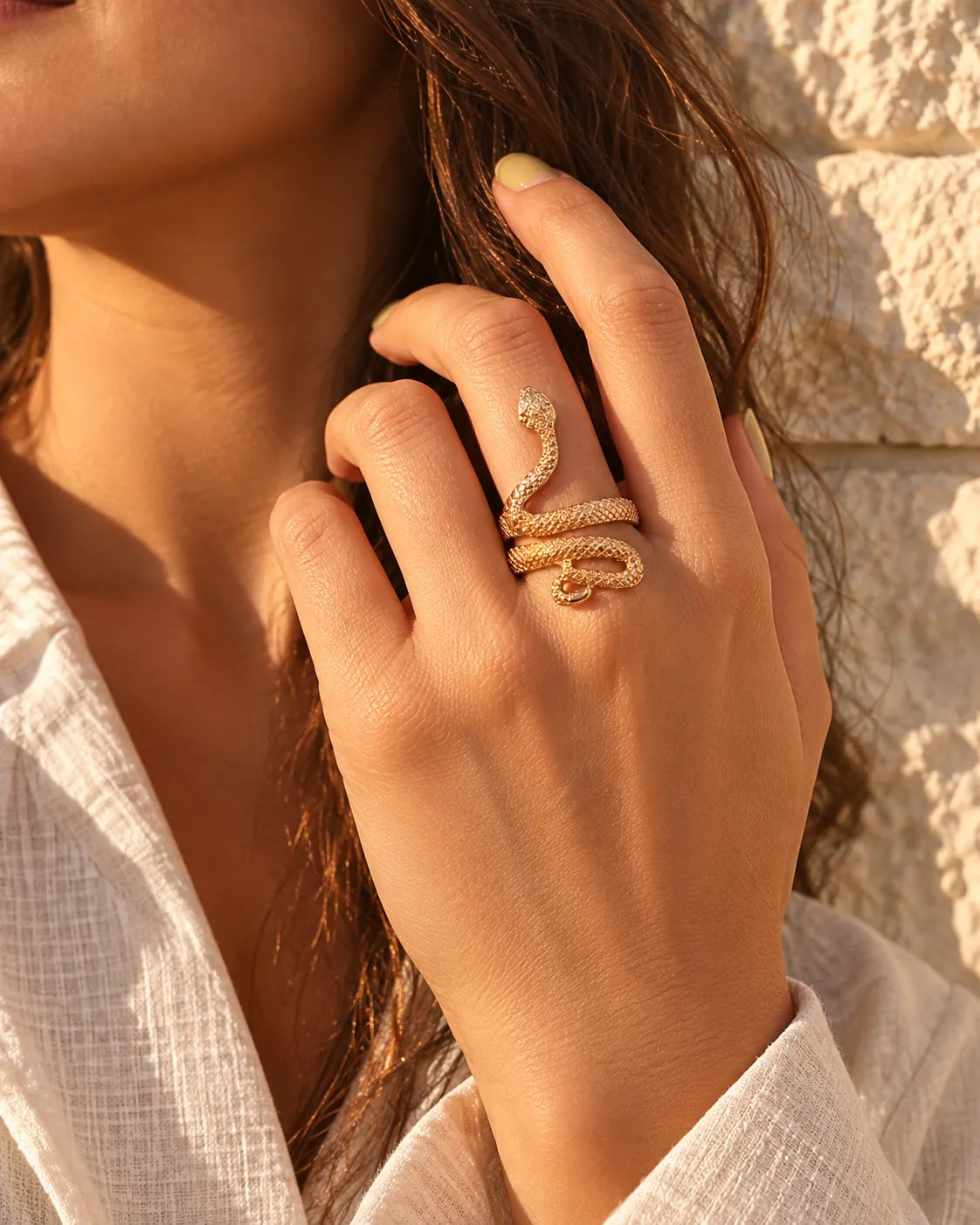 Model's hand near her face wearing the gold snake ring