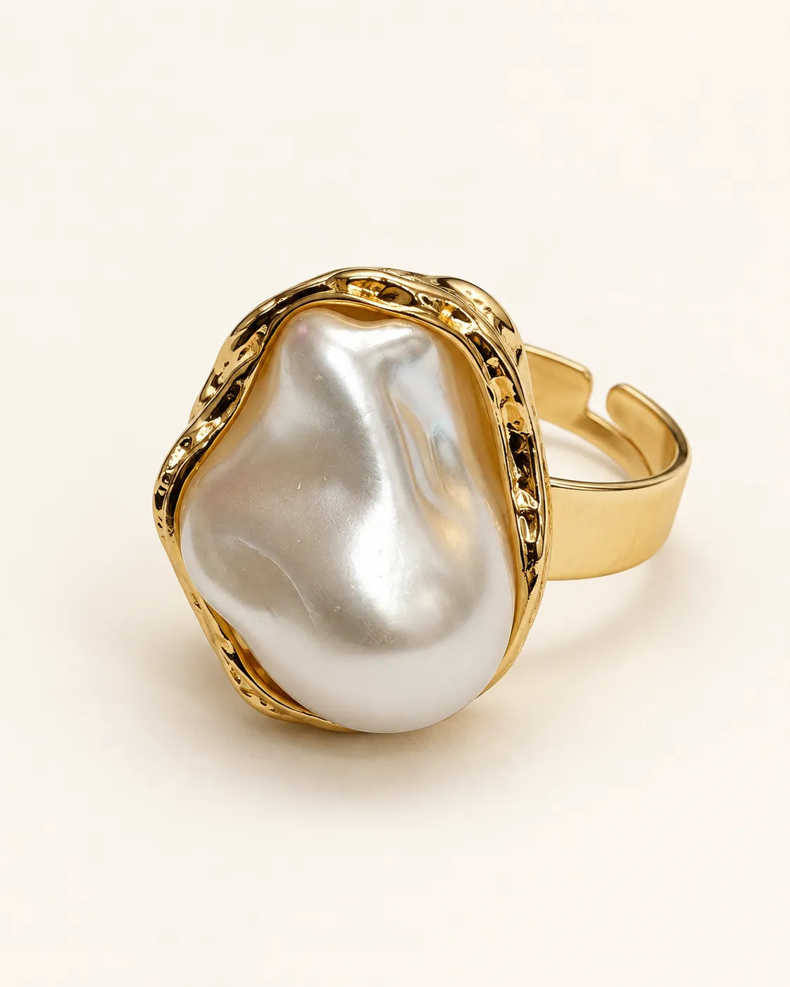 Gold-tone baroque pearl-look statement ring on a cream background