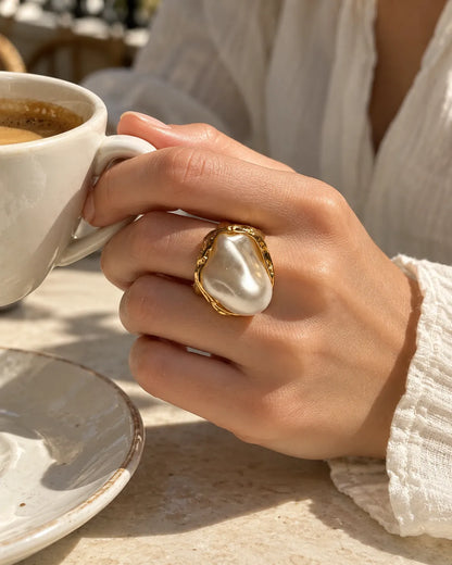 Hand holding a coffee cup wearing the gold baroque ring