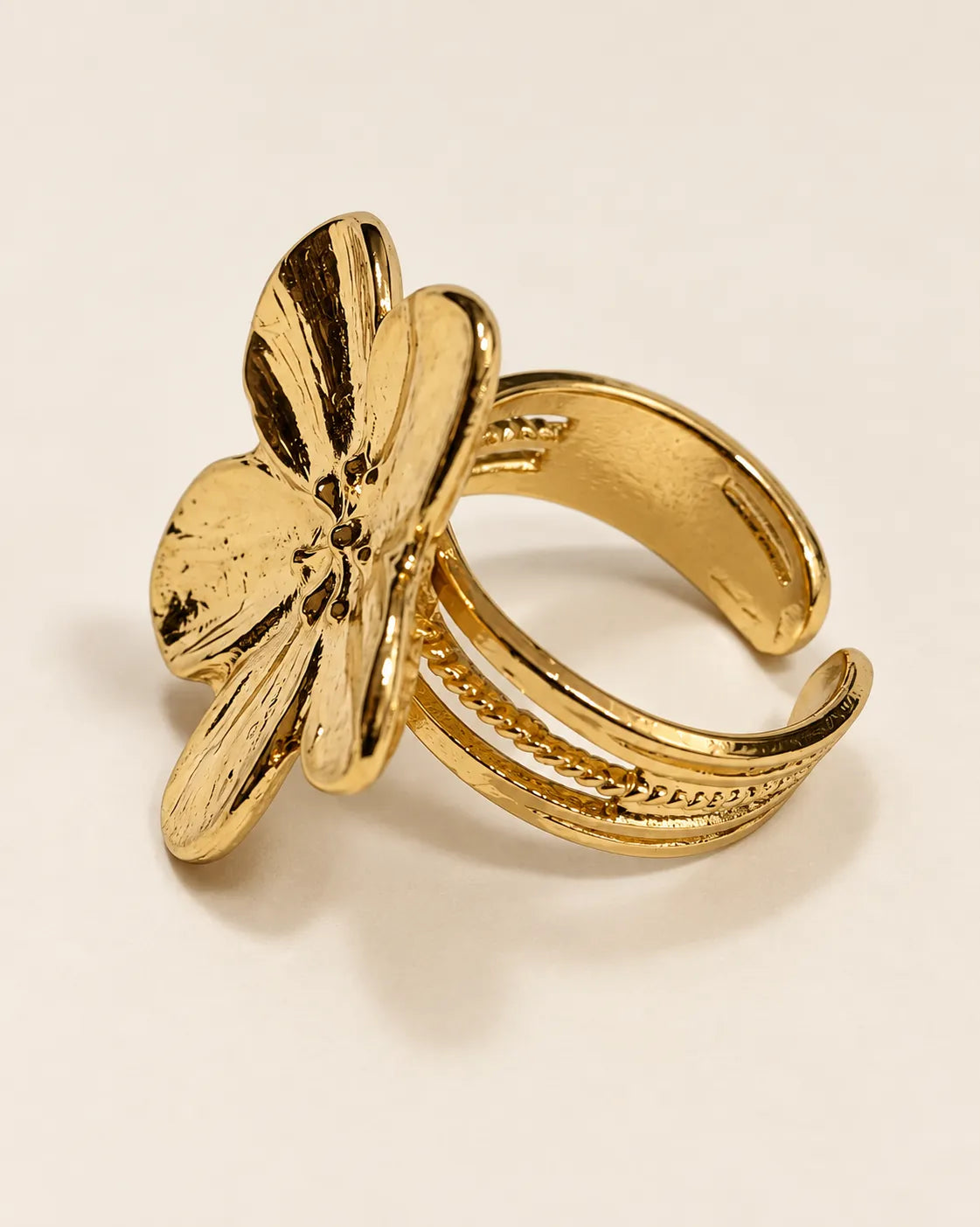 Side view of the gold flower ring showing the three-strand ridged open band