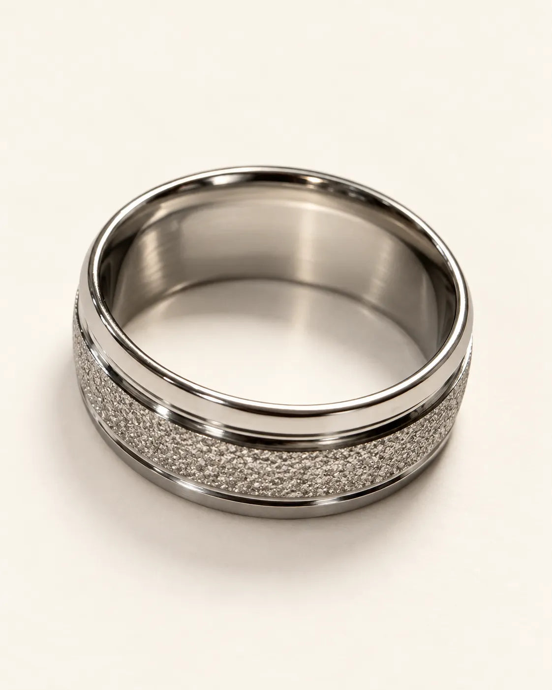 Silver textured band ring lying on its side showing the smooth inner surface