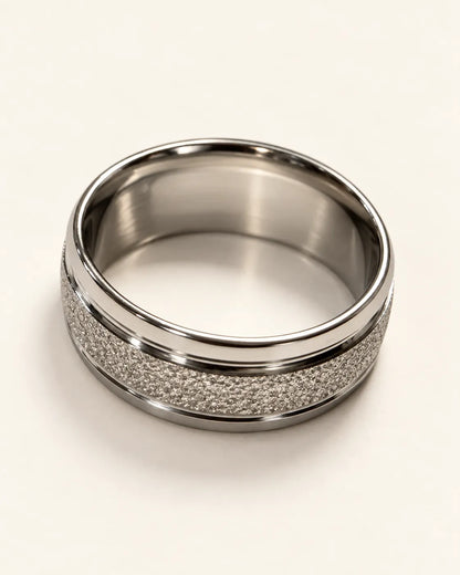 Silver textured band ring lying on its side showing the smooth inner surface