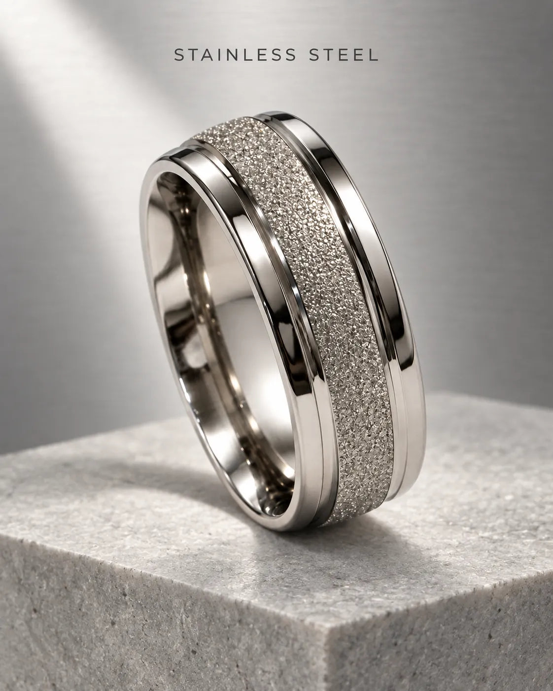 Silver textured band ring displayed on a grey stone block